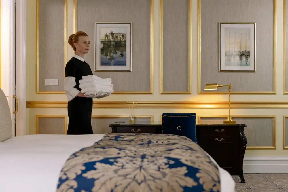 Gouvernante portant du linge dans une chambre d’hôtel